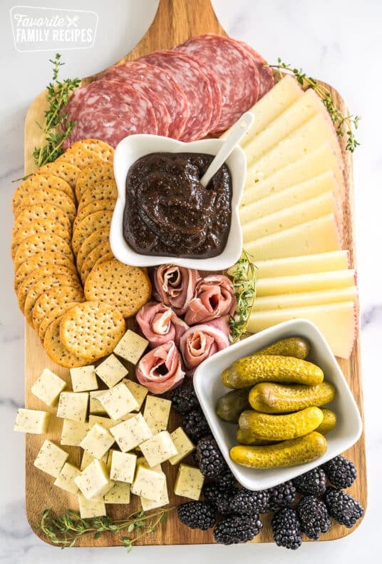 simple charcuterie board with meat, cheese, pickles, blackberries, crackers, and fig butter