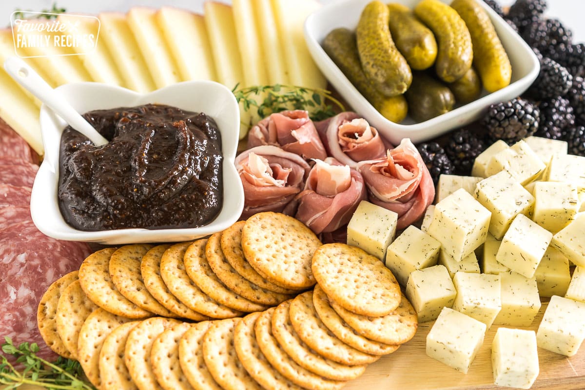 simple charcuterie board with meat, cheese, pickles, blackberries, crackers, and fig butter