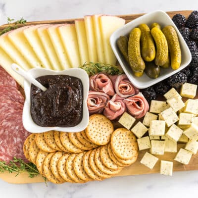 simple charcuterie board with meat, cheese, pickles, blackberries, crackers, and fig butter