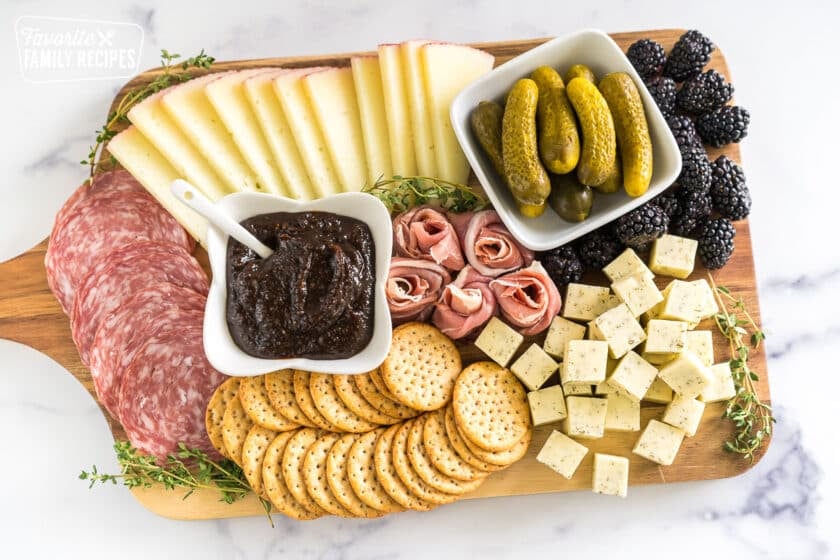simple charcuterie board with meat, cheese, pickles, blackberries, crackers, and fig butter