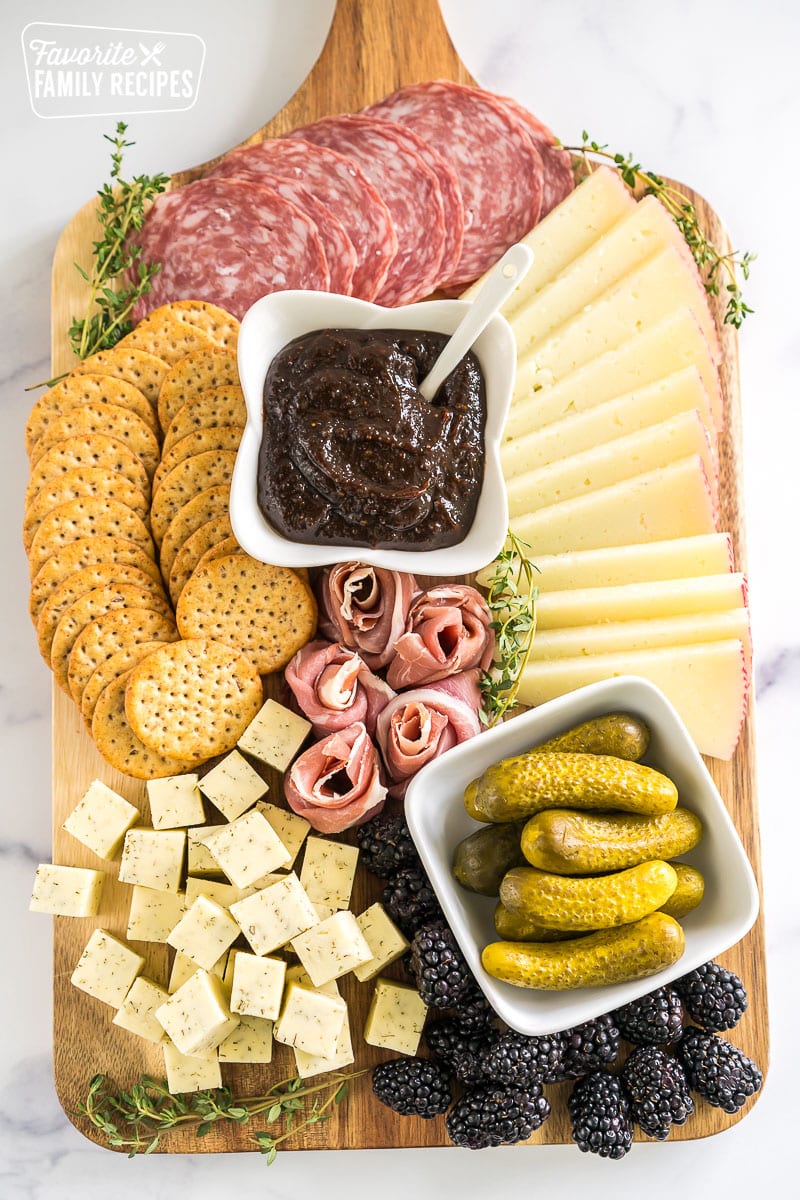 simple charcuterie board with meat, cheese, pickles, blackberries, crackers, and fig butter