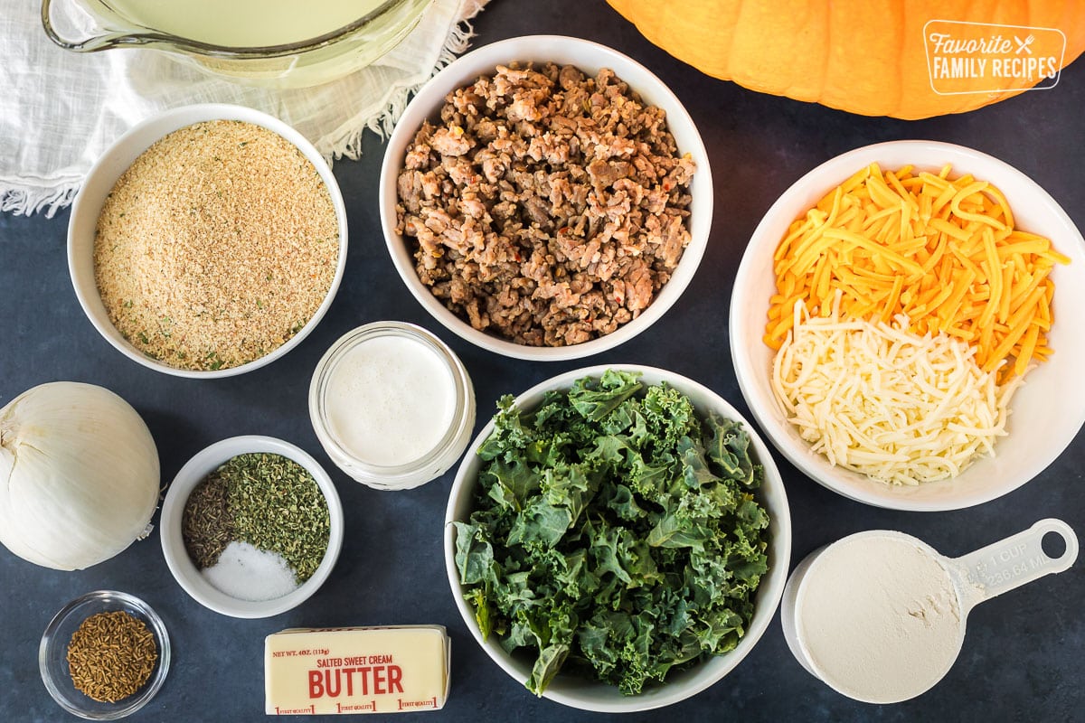Ingredients to make Soup in a Pumpkin including Italian sausage, cheese, Italian bread crumbs, spices, kale, onion, heavy cream, flour, butter chicken broth and a pumpkin.
