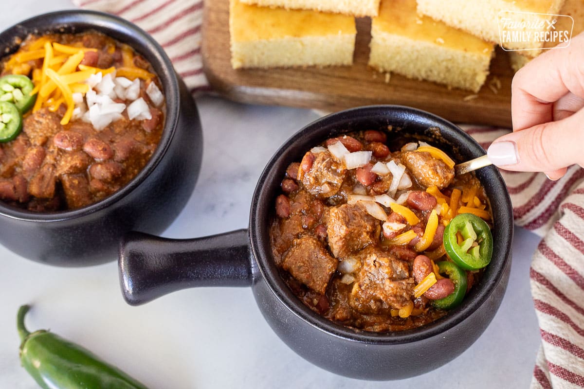 Hand holding a spoon while stirring a bowl of Texas Chili.