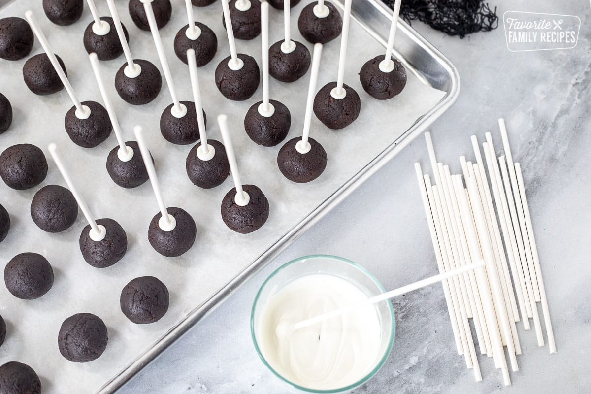 Dipping pepper stick in chocolate melt and inserting into cake ball for Halloween Cake Pops.