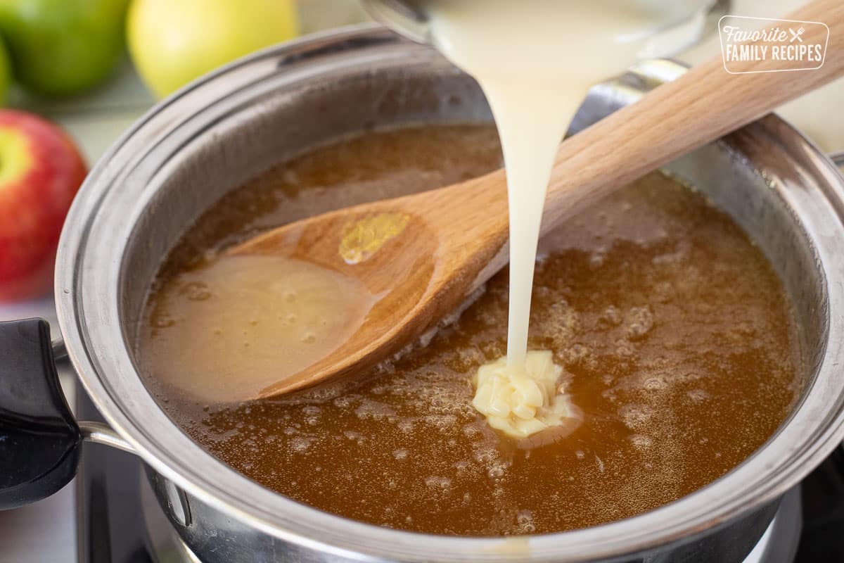 Pouring sweetened condensed milk into a pan of hot Caramel Apple Dip base.
