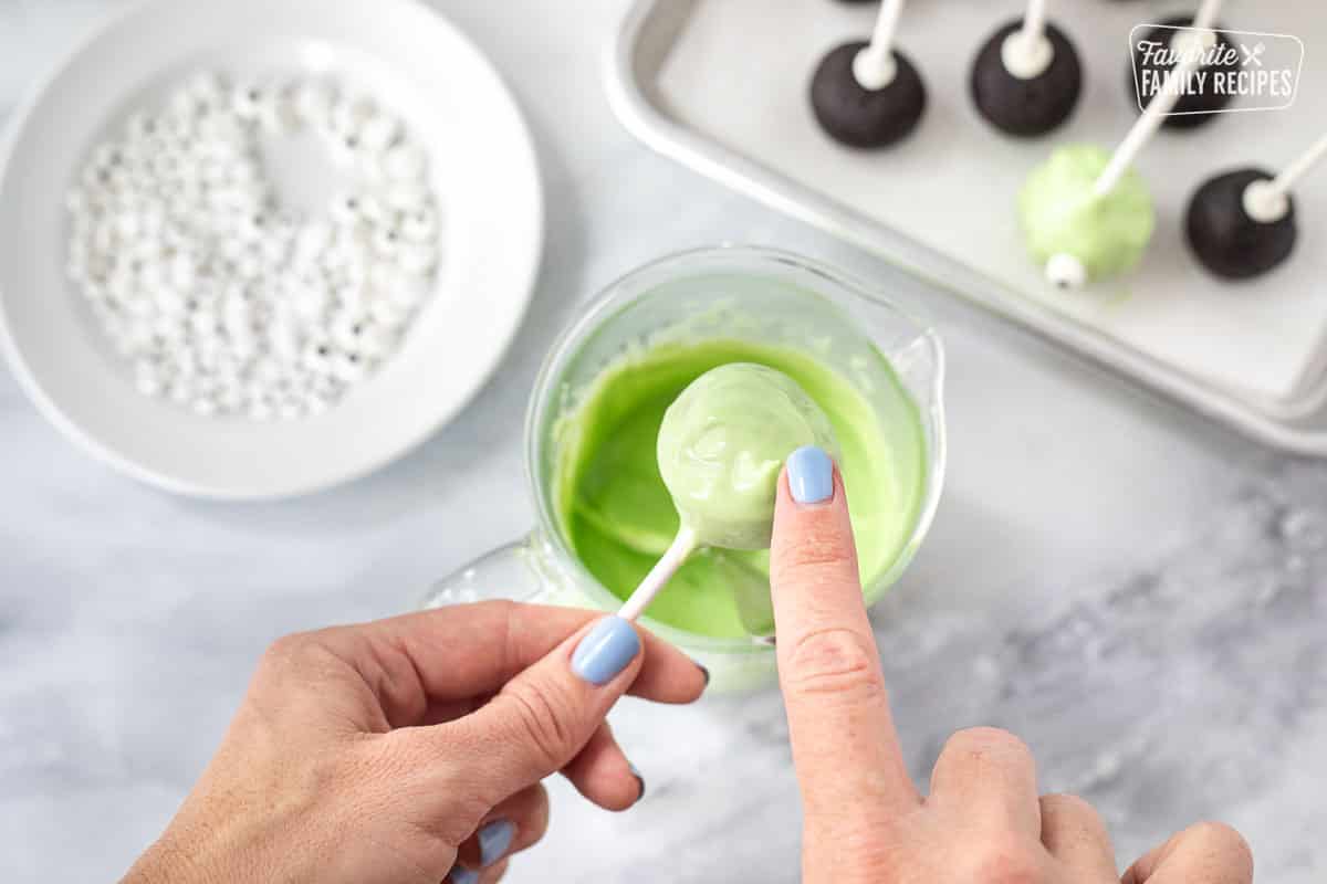 Swirling green candy melts with finger for Monster Halloween Cake Pops.
