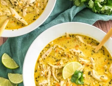 two bowls of thai coconut soup topped with lime and cilantro