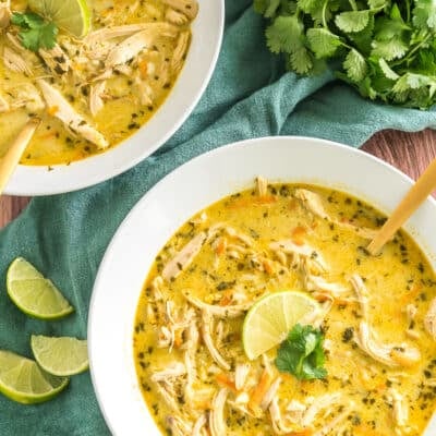 two bowls of thai coconut soup topped with lime and cilantro