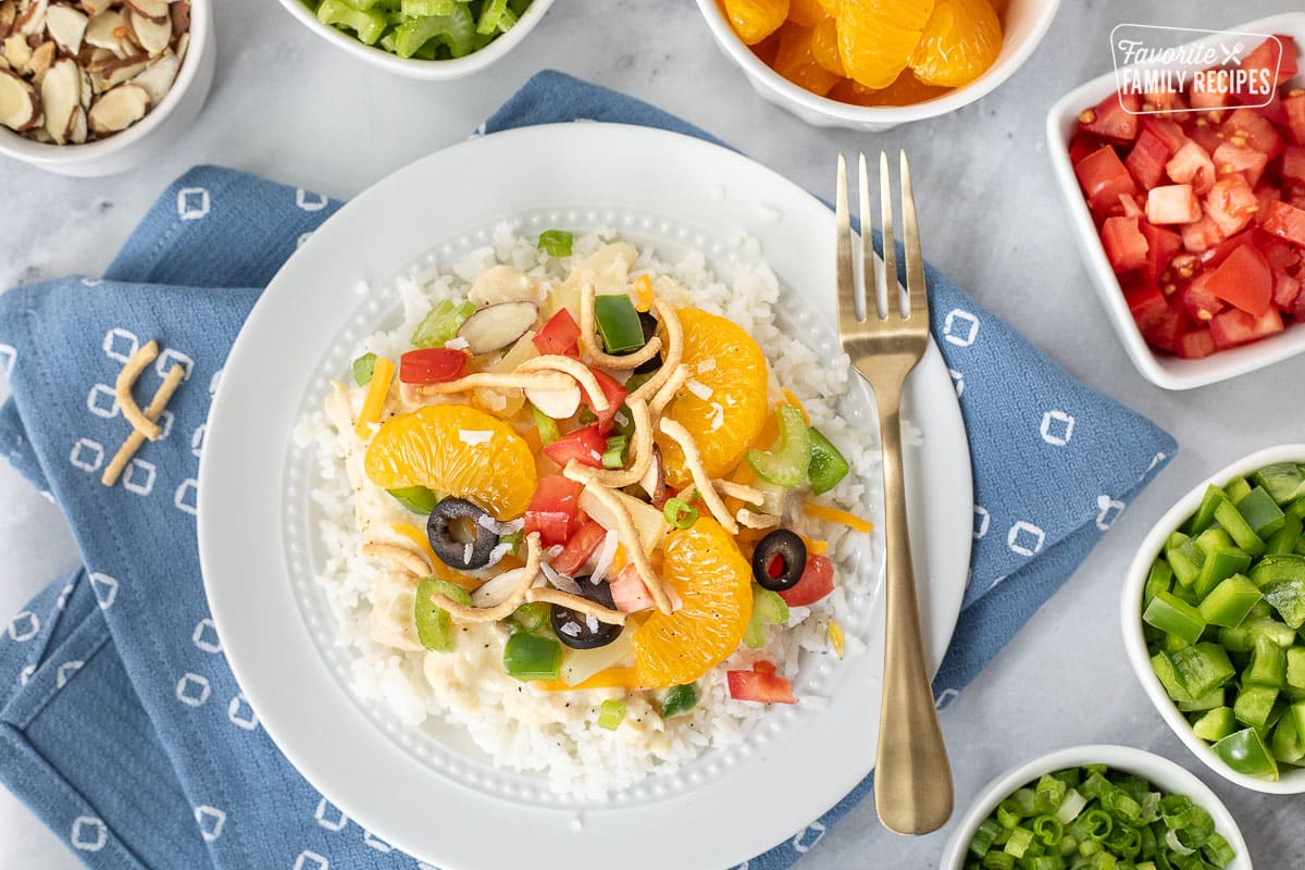 Constructed Hawaiian Haystack topped with green onion, cheese, rice noodles, green peppers, almond slices, tomatoes, celery, black olives, coconut, pineapple and mandarin oranges.