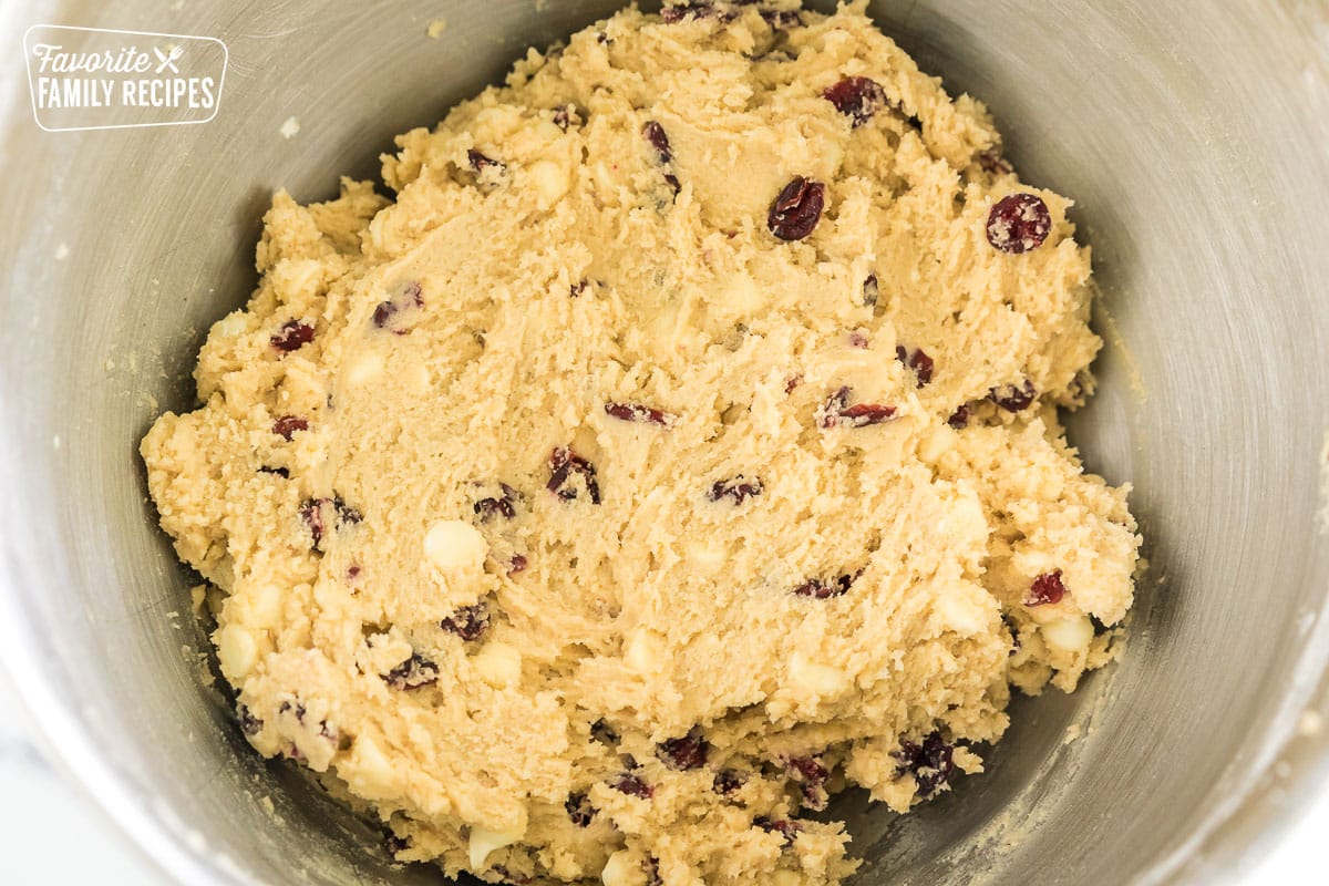 cookie dough in a mixing bowl with white chocolate chips and dried cranberries