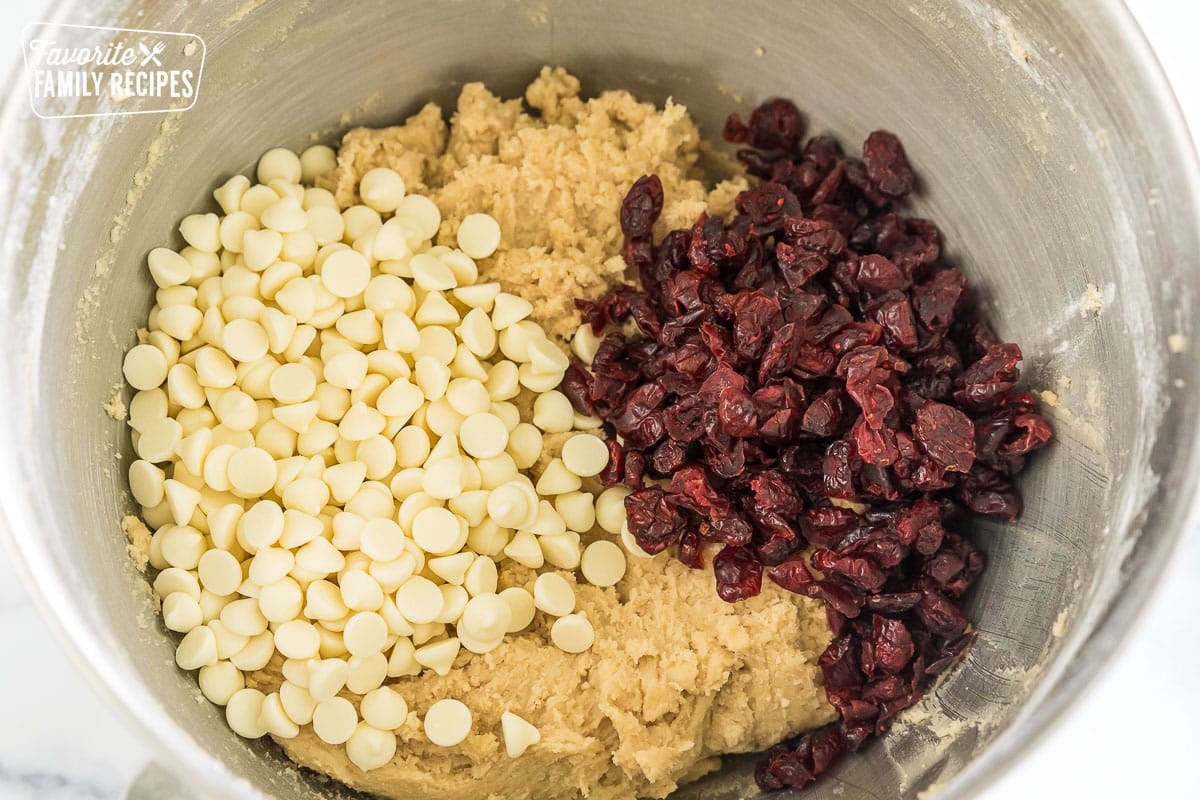 cookie dough in a mixing bowl with white chocolate chips and dried cranberries