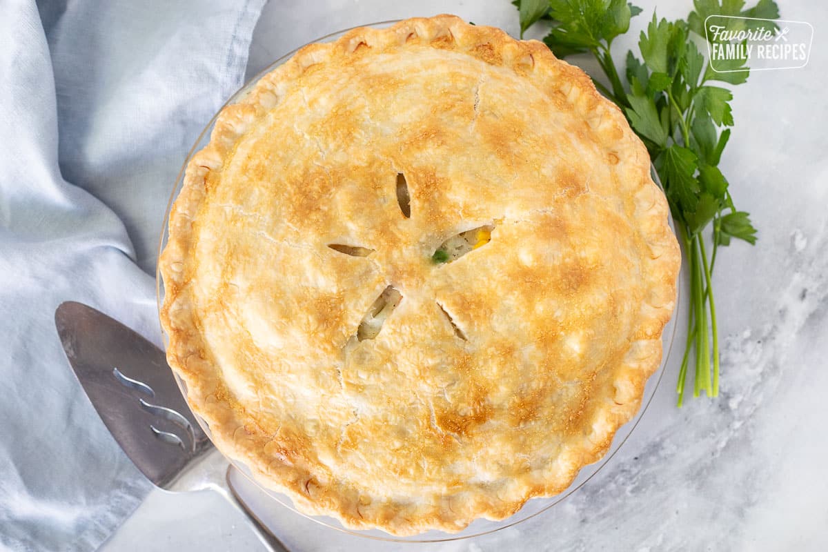 Whole Homemade Chicken Pot Pie next to parsley and a pie spatula.