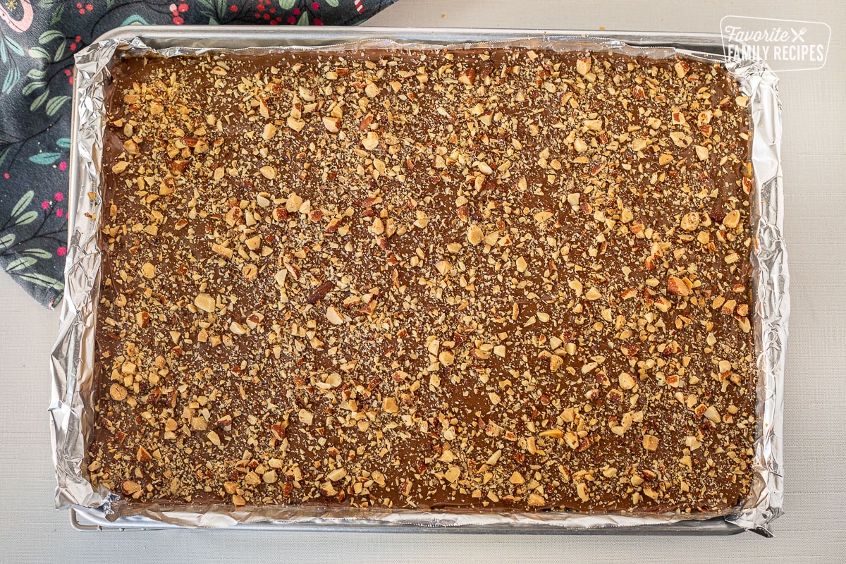 Chopped Almonds on top of Christmas Crack Candy in a baking sheet lined with foil.
