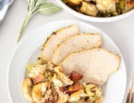Plate with sliced Turkey Breast and Bacon Stuffing. Bowl of Bacon stuffing on the side.