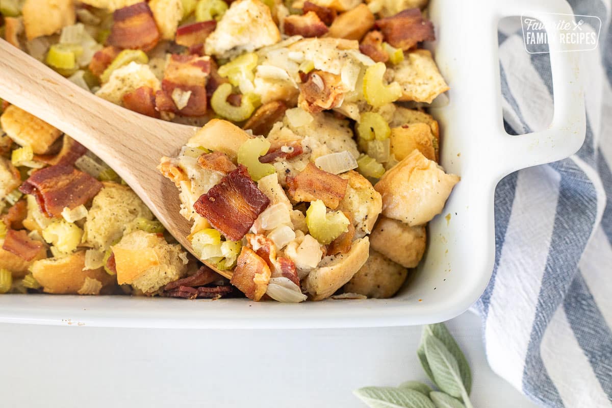 Wooden spoon resting in a casserole dish of Bacon Stuffing.