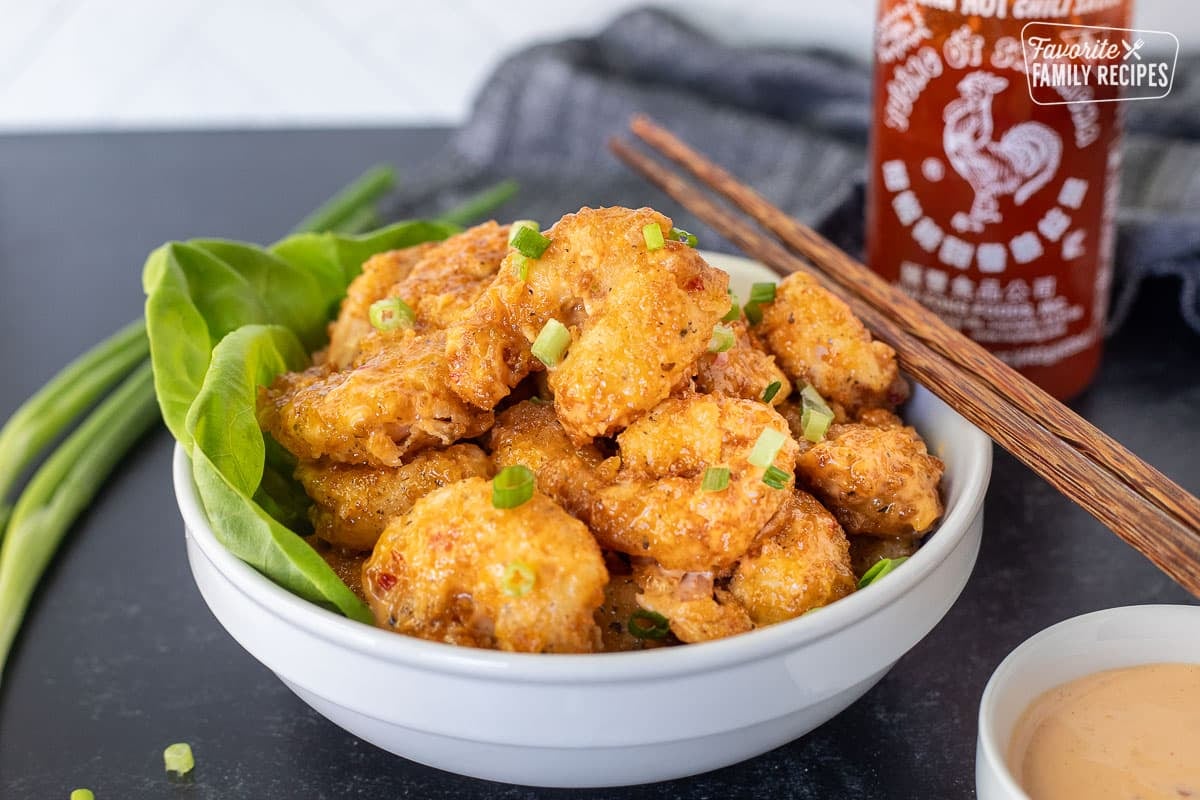 Bowl of Bonefish Grill's Bang Bang Shrimp with chop sticks and sriracha sauce on the side.