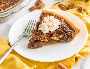 Brown Butter Pecan Pie on a plate topped with whipped cream