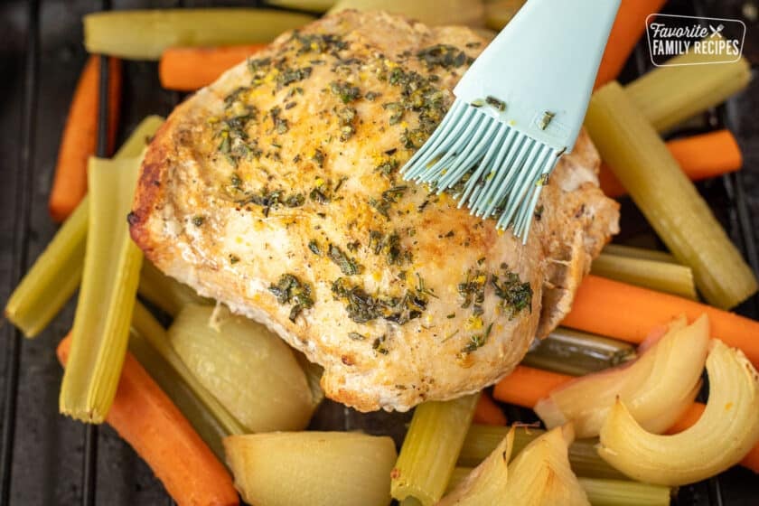 Brushing herb mixture on top of turkey breast.