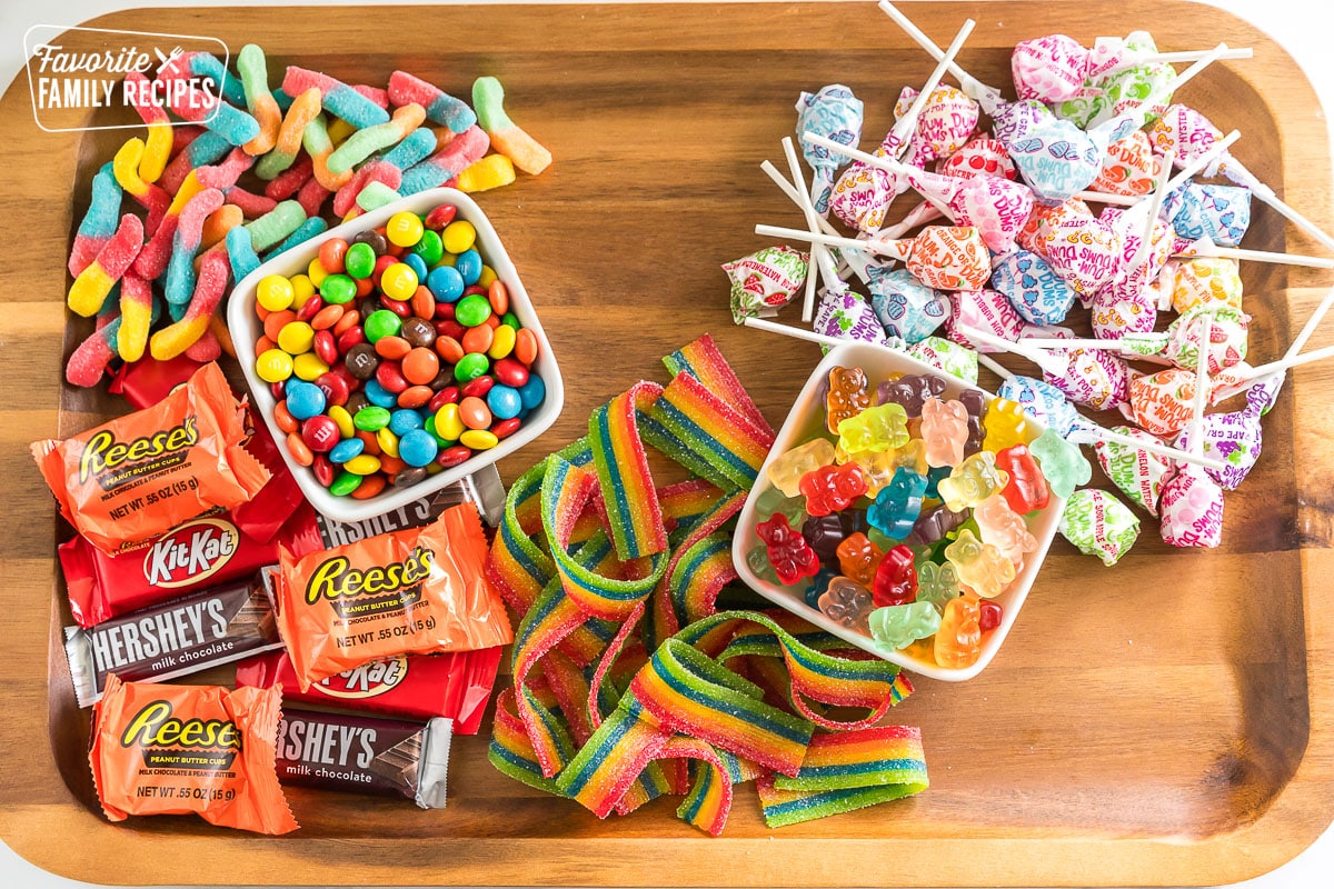 a wooden board with bowls of candy on it and some candy scattered around