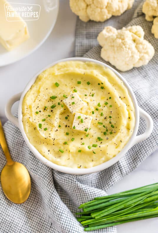 a bowl of cauliflower mashed potatoes topped with butter, pepper, and chives