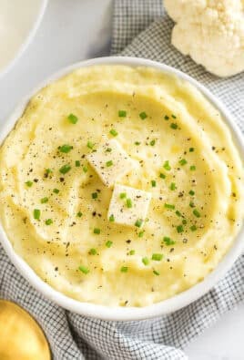 a bowl of cauliflower mashed potatoes topped with butter, pepper, and chives