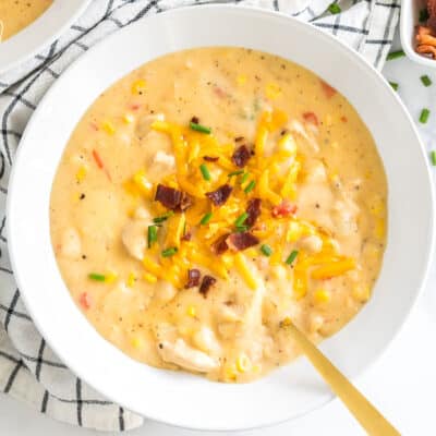 a bowl of chicken corn chowder topped with cheese, bacon, and chives