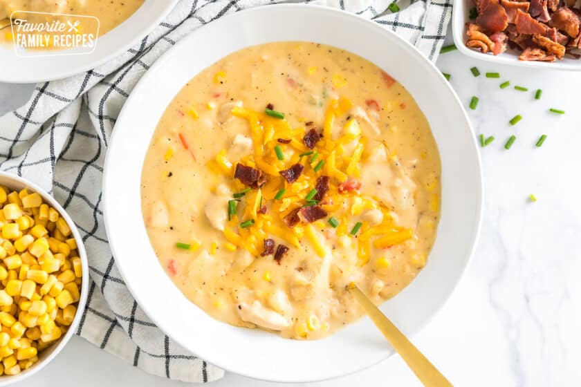 a bowl of chicken corn chowder topped with cheese, bacon, and chives