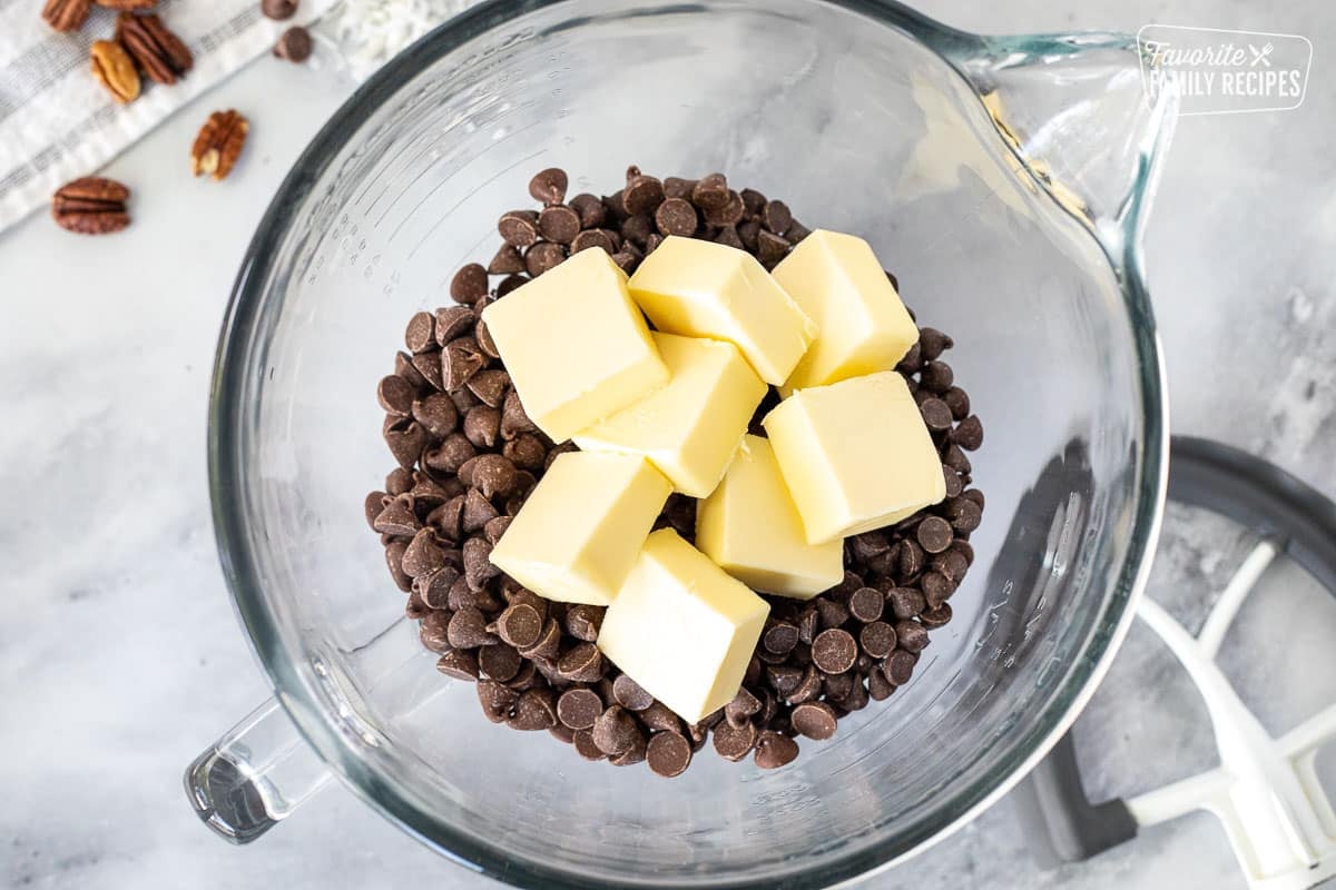 Mixing bowl of chocolate chips and sliced butter. Mixing paddle on the side.