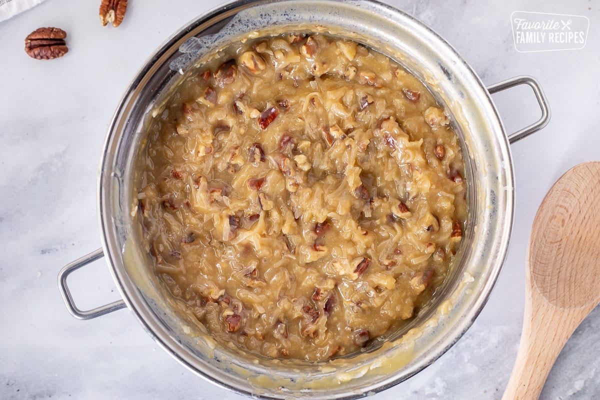 Coconut pecan topping in a heavy pot. Wooden spoon on the side.