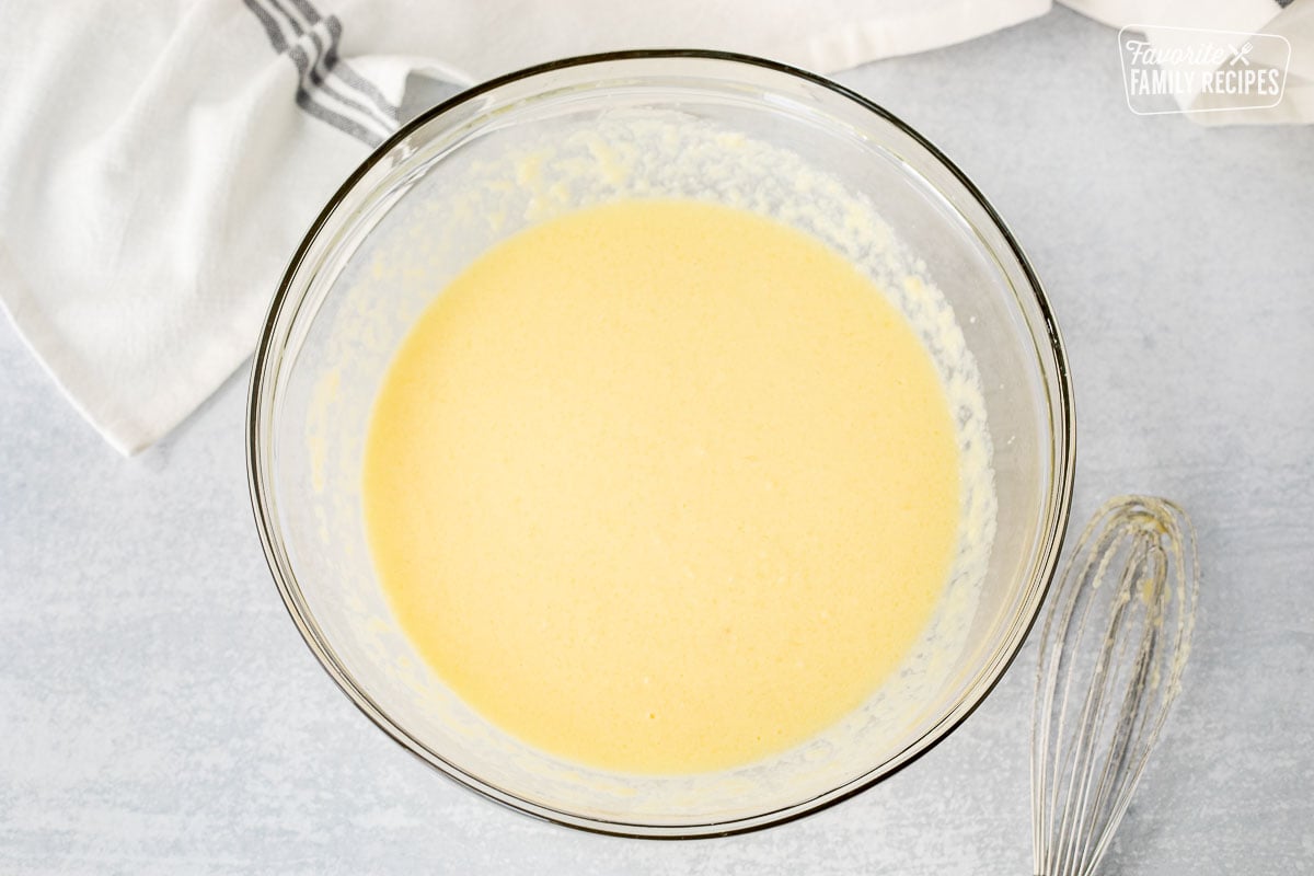 Bowl of wet ingredients for Cornbread. Whisk on the side.