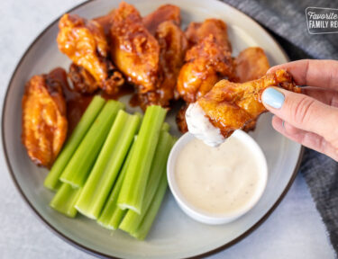 Hand holding a Winger's Wings with Freakin Amazing Sauce dipped in ranch dressing.