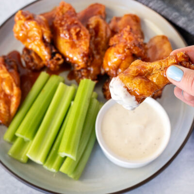 Hand holding a Winger's Wings with Freakin Amazing Sauce dipped in ranch dressing.