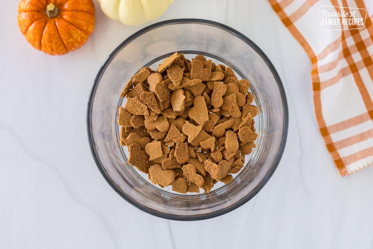 The first layer of crushed gingersnap cookies that have been spread evenly across the bottom of the trifle dish.