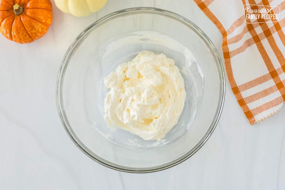 A bowl containing cream cheese that has been whipped and become soft and mixable.