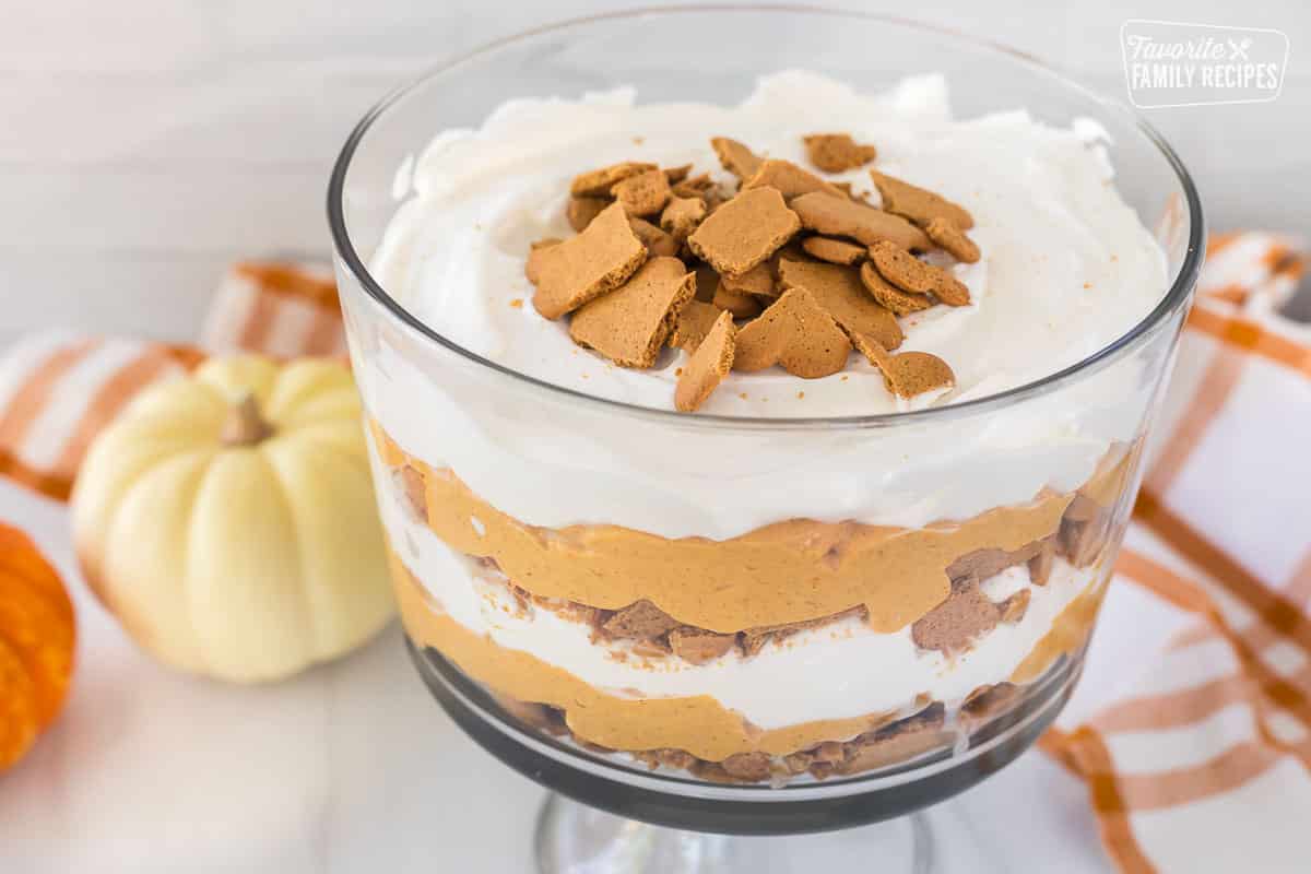 An angled view of easy pumpkin trifle with layers of whipped cream, pumpkin cheesecake, and gingersnap cookies.