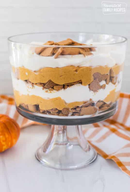A vertical view of easy pumpkin trifle with layers of whipped cream, pumpkin cheesecake, and gingersnap cookies.