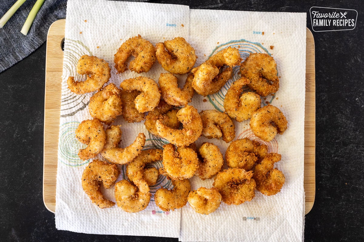 Cutting board with paper towels and fried shrimp.