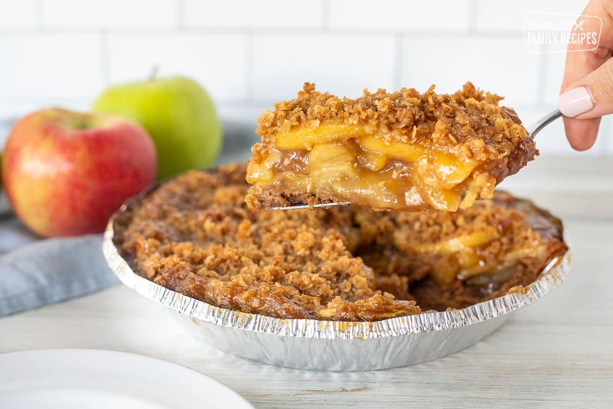 Hand holding a slice of Gluten Free Apple Pie over the pie.