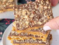 Hand grabbing a square of Saltine Cracker Toffee.