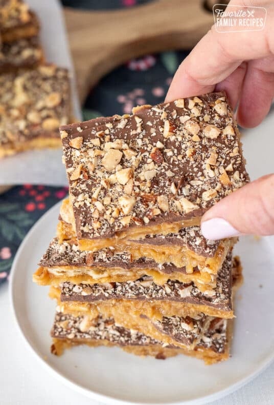 Hand grabbing a square of Christmas Crack Candy.