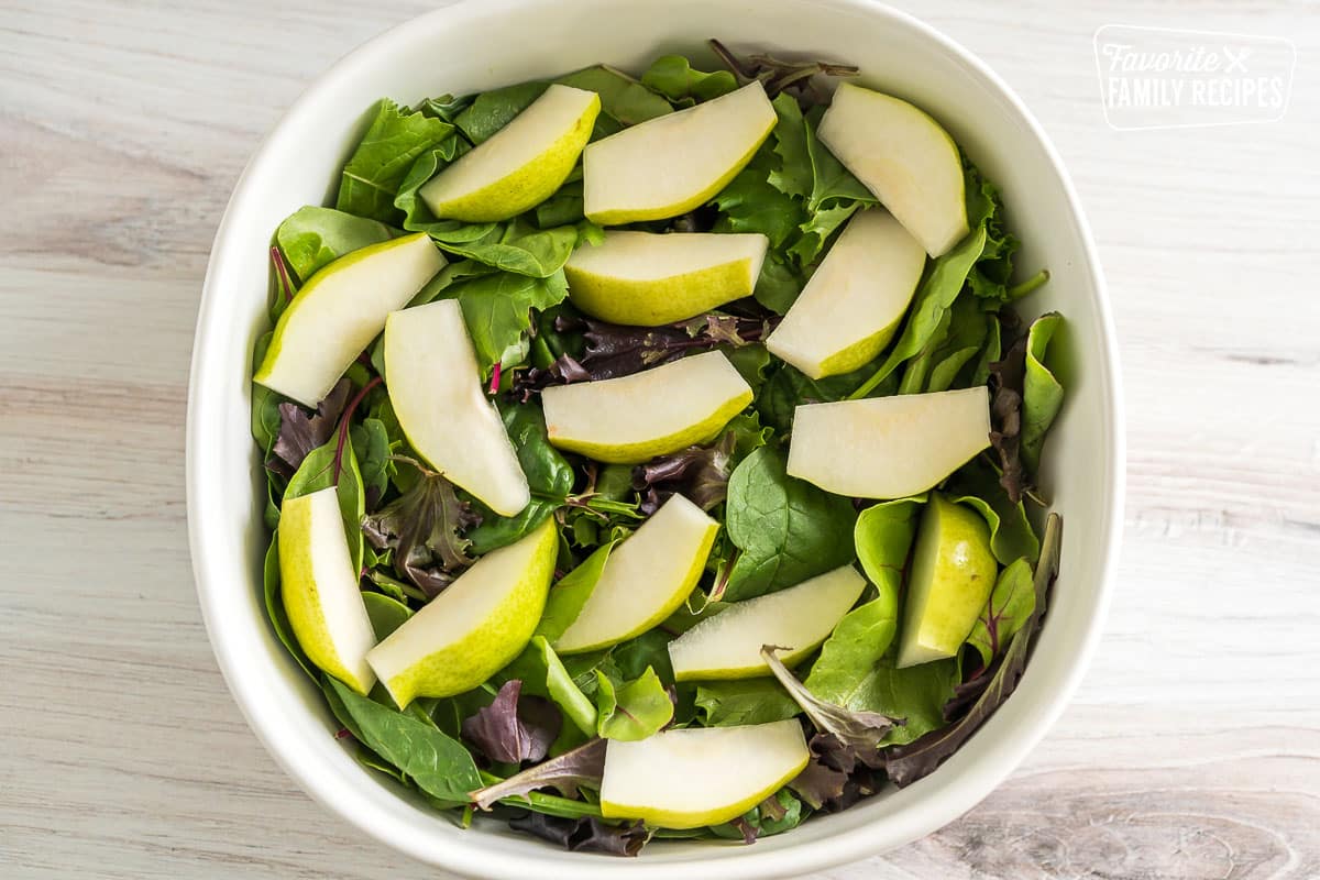 spring mix in a large bowl with sliced pears