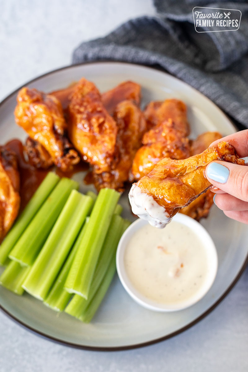 Hand holding a Winger's Wing with Freakin Amazing Sauce dipped in ranch.