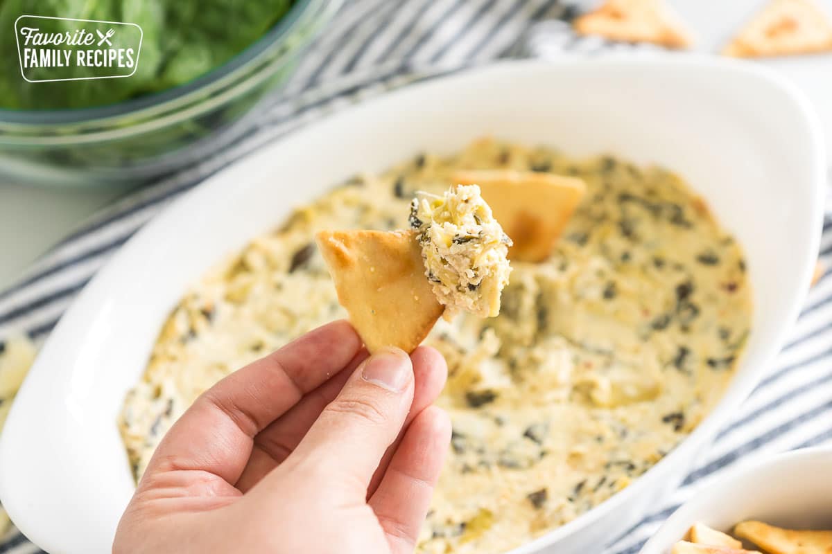 A pita chip dipped in spinach artichoke dip