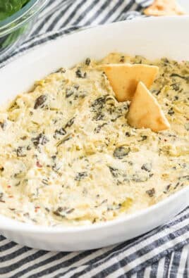 spinach artichoke dip in an oval baking dish with pita chips
