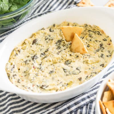 spinach artichoke dip in an oval baking dish with pita chips