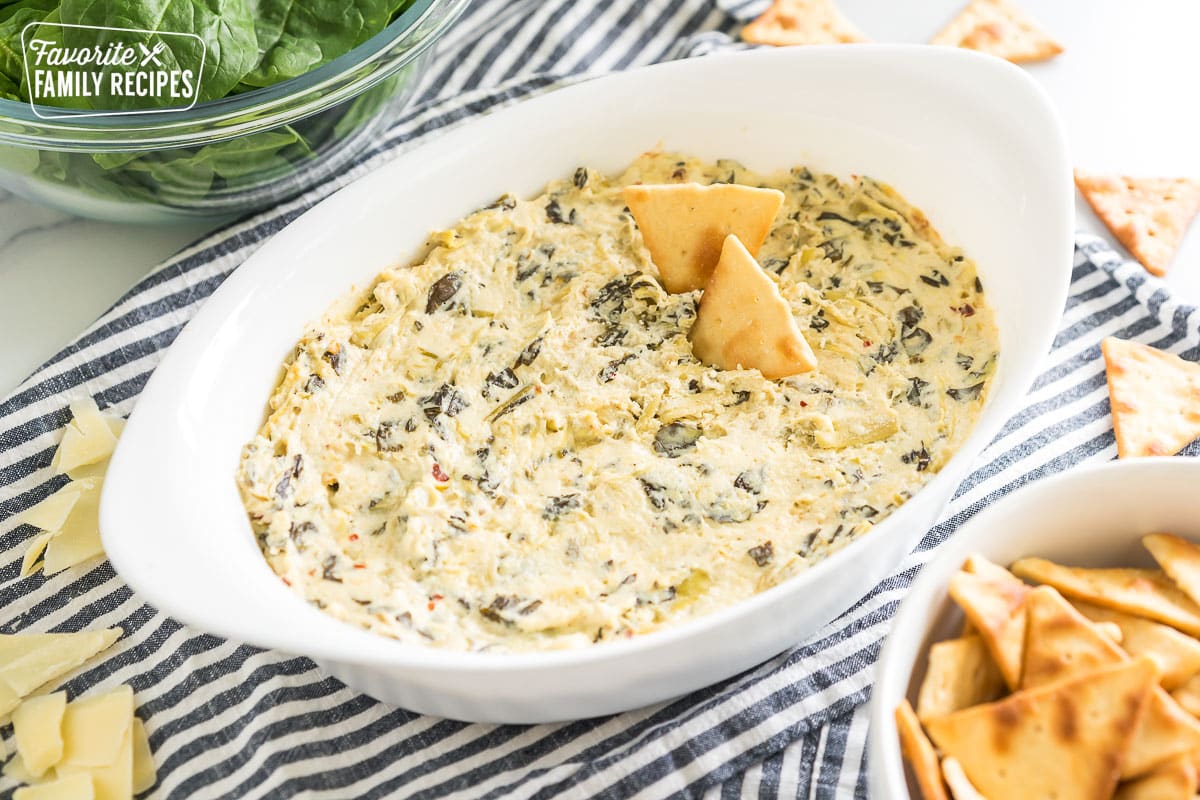 spinach artichoke dip in an oval baking dish with pita chips