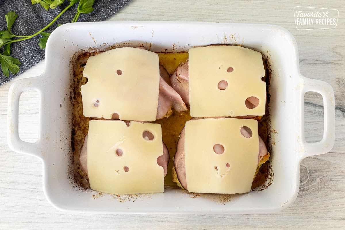 Ham and Swiss cheese slices on top of baked chicken.