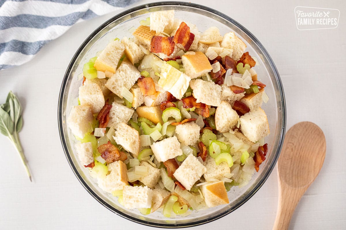 Mixing bowl with cubed bread, bacon, cooked celery and onion.
