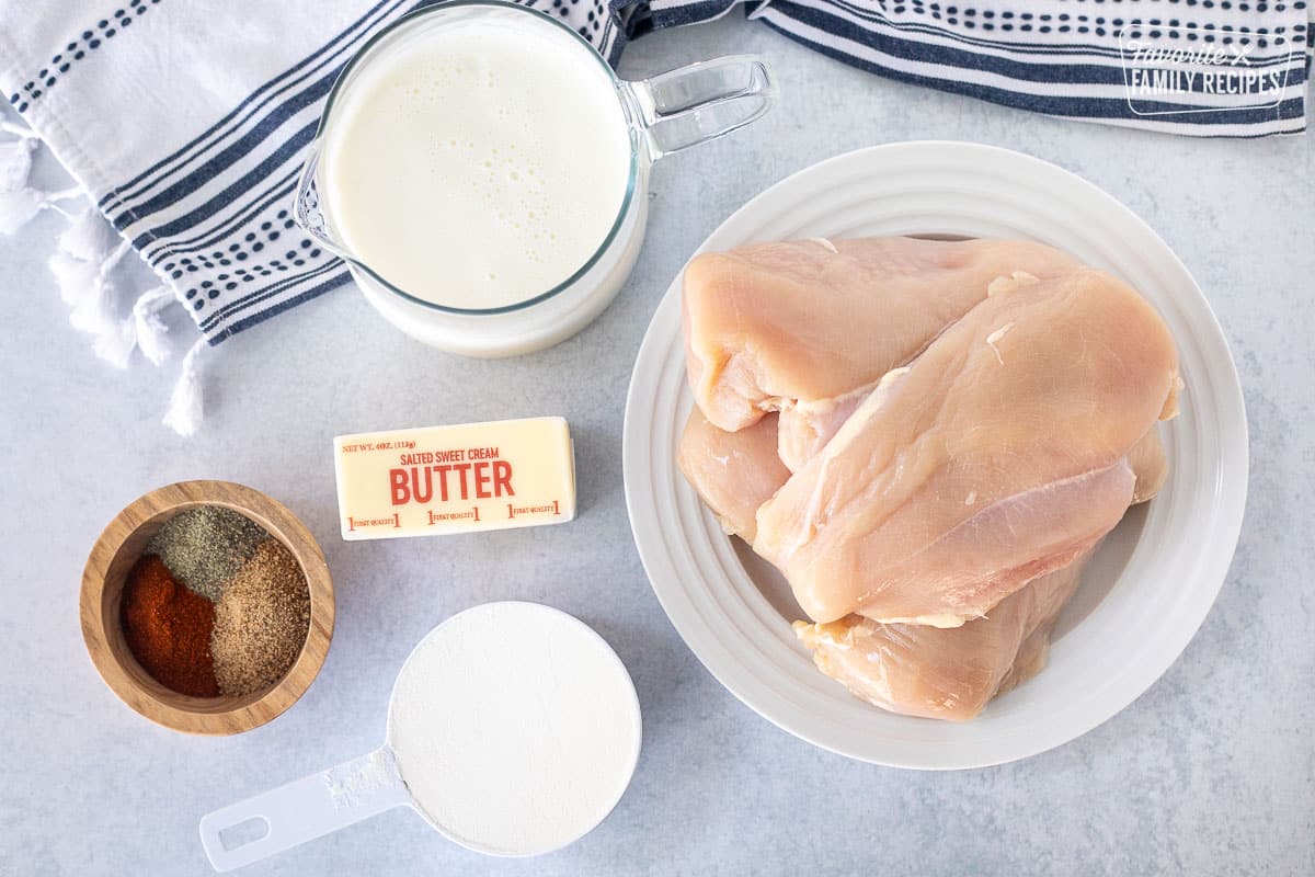 Ingredients to make Oven Fried Chicken including chicken breasts, buttermilk, butter, spices and flour.