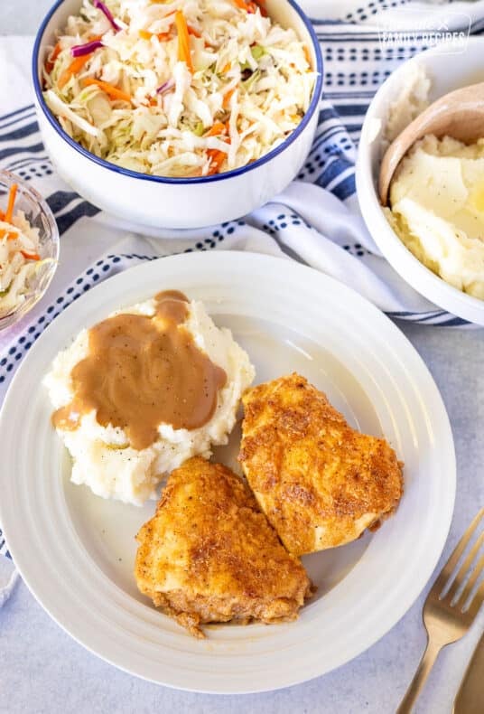 Plate with two pieces of Oven Fried Chicken, Mashed potatoes and gravy.